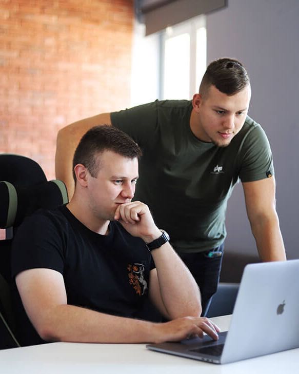 Two OVER Cloud designers at a laptop, reviewing a project together in the Łódź office